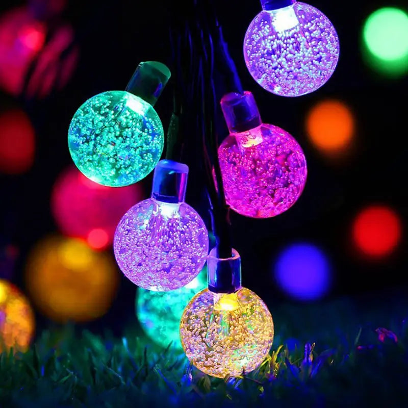 Solar-powered string of 50 LED lights with crystal balls for outdoor decoration.