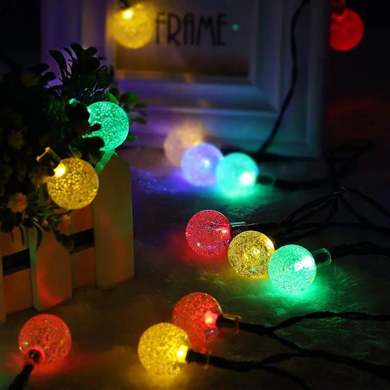 String of 50 LED fairy lights with crystal balls, solar-powered, ideal for outdoor use in streets, gardens, or as Christmas decor.